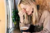 A pretty woman is relaxing in a coffee shop with a mug of cocoa. Morning coffee, friendly environment, pleasure and comfort.