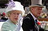 Kraljica Elizabeta 2002. sa suprugom, princem Philipom, na Ascotu nosi slamnati šešir s ljubičastim pernatim ukrasom, dizaj Fredericka Foxa, omiljenog kintičara od 1968.