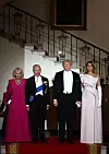 Melanijina gošća, kraljica Camilla odabrala je dugu večernju haljinu britanske dizajnerice Fione Clare, u jarko ružičastoj nijansi s dugim rukavima i blago proširenim rubom
