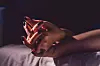Close up on female young woman's girl's beautiful hands with black nail polish in dark room holding crossed fingers on the bed sheet.