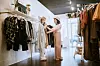 A fashionable Hispanic woman works in her small retail clothing store, selling new fashion items. She helps a customer select and try on clothes. Representing, local, personable, small business. Shot in Seattle, Washington, USA.