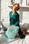 cheerful lovely woman on bed in green silk pajamas sjow kiss gesture