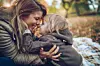 Happy mother and her small son having fun while touching with noses in autumn day.