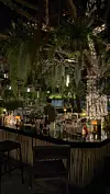 Raskošan vanjski bar u bujnom, osvijetljenom zelenom okruženju