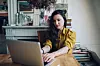 Female novelist, blogger, freelancer designer or a photographer, typing on the laptop keyboard in her bedroom in the beautiful bright apartment in Paris city center, in Montmartre district. Retro processed with vibrant colors. Fashionable blogger, freelancer, work from home concepts in Paris, France.