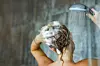 Back view of a woman washing her hair with a shampoo in bathroom. Copy space.