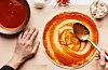 Chef cooking pizza, spreading tomato sauce on daugh with ingredients around, top view