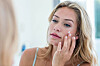 Smiling pretty woman applying cream on her face in bathroom,Image: 280469850, License: Royalty-free, Restrictions:, Model Release: yes, Credit line: -/Wavebreak/Profimedia