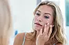 Smiling pretty woman applying cream on her face in bathroom,Image: 280469850, License: Royalty-free, Restrictions:, Model Release: yes, Credit line: -/Wavebreak/Profimedia