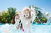 Happy family playing in blue water of swimming pool on a tropical resort at the sea. Summer vacations concept