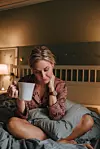 Real woman in pyjamas relaxing in bedroom with tea Photo taken indoors in bed unretouched photo with natural light