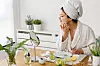 Young woman cleaning face with natural cosmetics. How to get clear and glowing skin. Portrait of young woman with clay face mask on wearing bathrobe. Homemade Face Mask