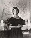 Portrait of Canadian-born beautician and cosmetics entrepreneur Elizabeth Arden (1878 - 1966) dressed in a ball gown as she clasps her hands together and stands in front of a framed piece of art, 1947. (Photo by Hulton Archive/Getty Images)