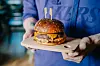 Smeš Vol.2 burger s potpisom chefa Denija Srdoča sastoji se od dry aged juneće pljeskavice, cheddar sira, Devil umaka, hrskavog luka i ragua od gljiva u brioche pecivu