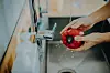 Close up of man's hand washing red bell pepper under running water in the kitchen