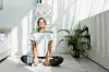 beautiful happy girl with closed eyes practicing yoga in lotus position in bedroom in the morning