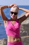 Blonde female person in sunglasses adjusting her ponytail. She holding scrunchie in her mouth