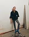 Jakna s detaljem volana na rukavima i našivenim džepovima, top s povišenom kragnom zlatno-crnog prugastog uzorka i kapri hlače kontrastnog retro jacquard uzorka, sve Varteks. Naušnice privatno vlasništvo; čarape i salonke iz fundusa stilista