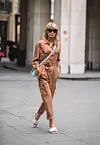 PARIS, FRANCE - FEBRUARY 29: Gitta Banko is seen wearing brown jumpsuit by Madeleine fashion, white lido mules by Bottega Veneta, a topas colored padded cassette bag by Bottega Veneta and sunglasses by Mykita x Maison Margiela during Paris Fashion Week - Womenswear Fall/Winter 2020/2021 : Day Six on February 29, 2020 in Paris, France. (Photo by Christian Vierig/Getty Images)