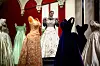 A member of the Royal Collection Trust staff (C) poses amongst the evening gown collection, during a media preview of the exhibition ‘Queen Elizabeth II: Her Life in Style‘ at the King�s Gallery in Buckingham Palace in London on April 9, 2026. The largest exhibition showcasing Queen Elizabeth II�s fashion ever staged is being held from April 10 to October 18, 2026. (Photo by Henry NICHOLLS/AFP)/RESTRICTED TO EDITORIAL USE - NO MARKETING - NO ADVERTISING CAMPAIGNS