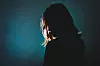 silhouette of depress woman standing in the dark with light shine behind