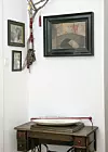 Kutak sa starim obiteljskim fotografijama i postoljem šivaće mašine koje služi kao stolić