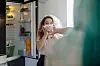 Blond young woman by the open fridge taking a bowl of mushrooms with surprise