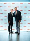 Oliver Lušić i Tomislav Paškvalin u odijelima poziraju ispred zida s logotipom HPO-a.