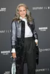 Andie MacDowell u kožnoj jakni, bijeloj košulji i širokim hlačama pozira pred filmskim zidom u Parizu.