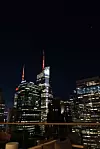 Noćni pogled na Manhattan s osvijetljenim tornjem One World Trade Center u središtu.