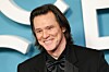 Jim Carrey u crnom smokingu nasmiješen pozira pred pozadinom nagrada César u Parizu.