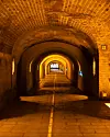 Prazan tunel od opeke s lučnim svodom, toplom rasvjetom i oznakom 22 na desnom zidu.