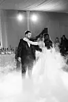 Mladoženja u odijelu i mladenka u bijeloj vjenčanici plešu kroz niski dim pred uzvanicima.