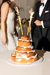 Svadbena torta s prskalicama ispred mladenke u bijeloj haljini i mladoženje u crnom odijelu
