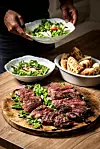 Ruke Tihomira Hojsaka i Filipa Novosela poslužuju salatu uz narezane steakove i zapečene zalogaje.