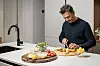 Filip Novosel u tamnom džemperu priprema steakove i povrće u modernoj kuhinji.