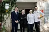 Četvero članova hotelskog tima u formalnoj i kuharskoj odjeći ispred hotelskog ulaza.