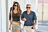 George i Amal Clooney hodaju uz zračnu luku; Amal nosi crni top i suknju, a George polo majicu i hlače.