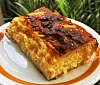 Komad zlatno zapečene slane pite s tamno hrskavom koricom na bijelom tanjuru.