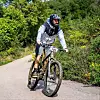 Biciklist u kacigi i sportskoj odjeći vozi brdski bicikl po šumskoj cesti.