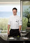 Chef u bijeloj uniformi s logotipom JRE-a stoji uz stol u restoranu hotela VILA ROVA na Krku.