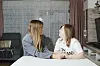 Ana Maria i Kristina Vajda sjede za bijelim stolom i razgovaraju u dnevnom boravku.