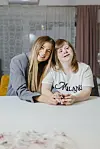 Ana Maria i Kristina Vajda sjede za stolom; jedna nosi sivi sako, a druga bijelu majicu s natpisom.