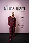 Muškarac u bordo prugastom odijelu i sunčanim naočalama pozira pred zidom Gloria Glam.