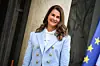 Melinda Gates u svijetloplavom sakou ispred Elizejske palače, uz zastavu Europske unije.