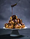 Topping profiterole tower with melted dark chocolate