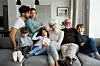 Milti generational family is posing on the sofa in their living room.