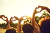 Hands of group friends in the shape of a heart against the sunset. Love and relationship friendship concept