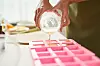 Close-up image of woman pouring soap mixture into plastic form