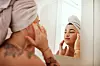 Shot of an attractive young woman inspecting her face in the bathroom mirror